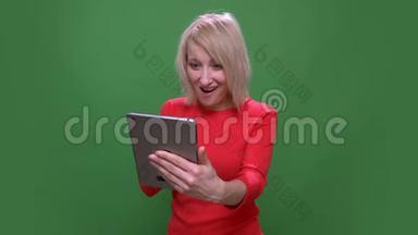 中年<strong>短发</strong>女商人在平板电脑上用视频聊天，高兴地被孤立在<strong>绿色</strong>的色彩背景上。